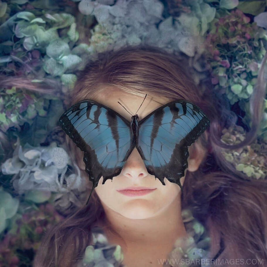 girl head lying in flowers with a blue butterfly covering her eyes like a mask photography composite